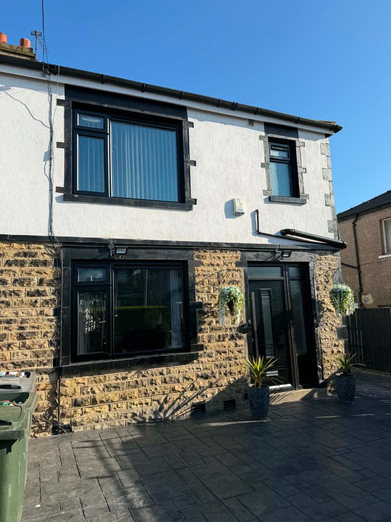 Completed anthracite windows and door on a stone and render house